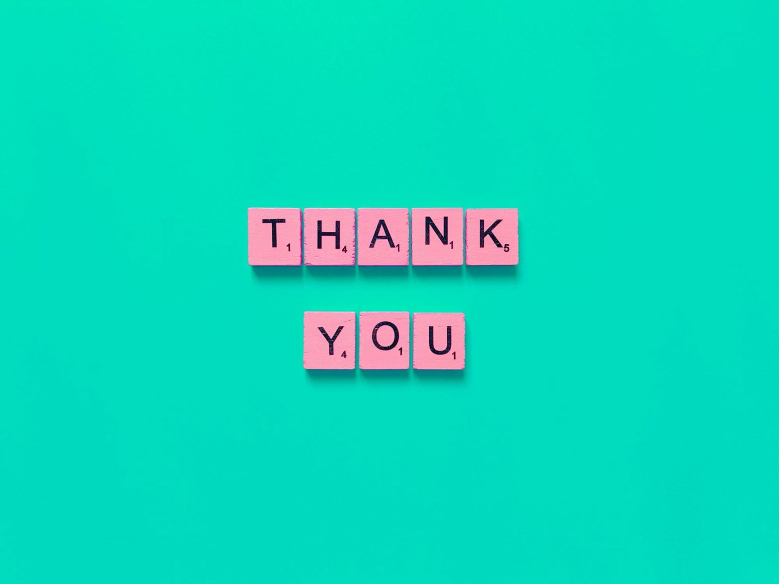 pink scramble pieces spelling thank you against green background to symbolizing saying thank you for your order