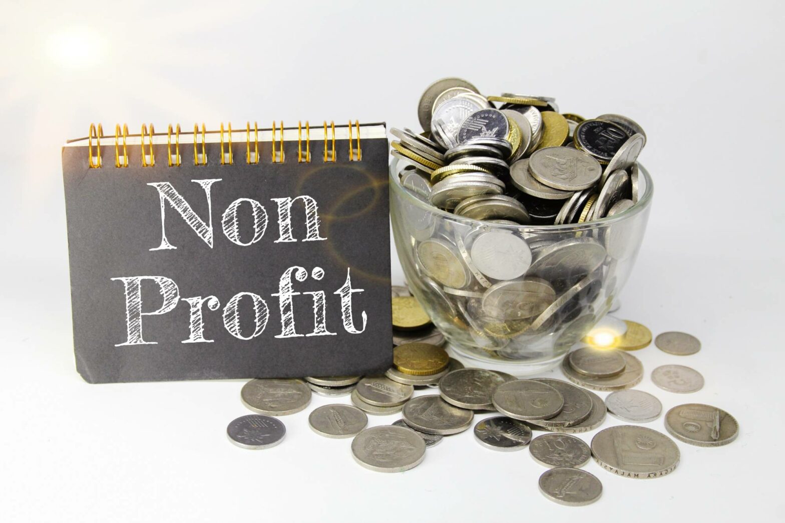 nonprofit written notepad cover next to cup full of coins symbolizing how to start a nonprofit
